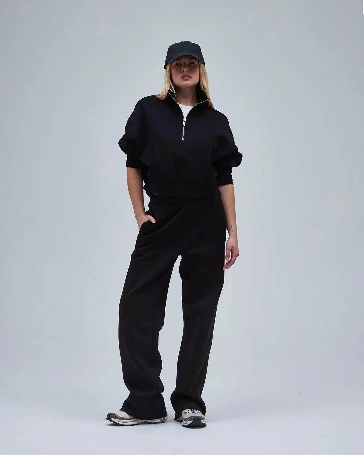 A woman in black straight-leg sweatpants & a sweatshirt