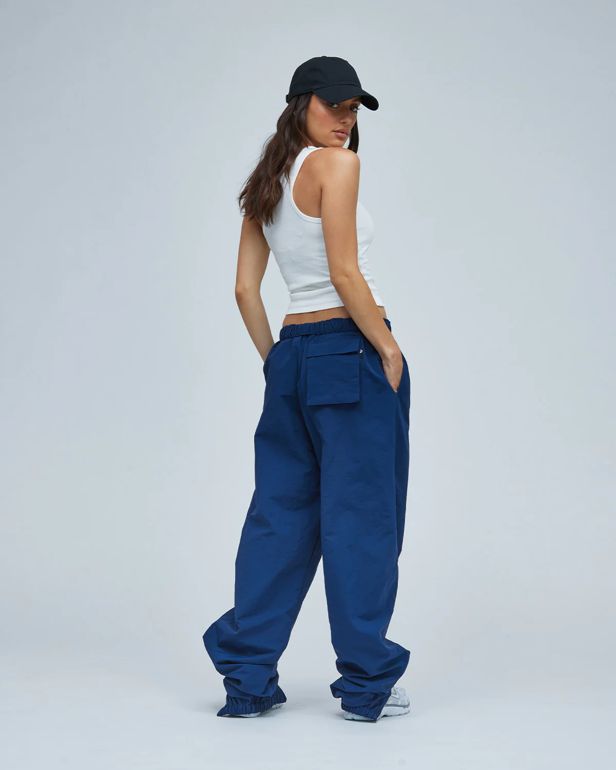 A woman wearing blue track pants and a white tank top