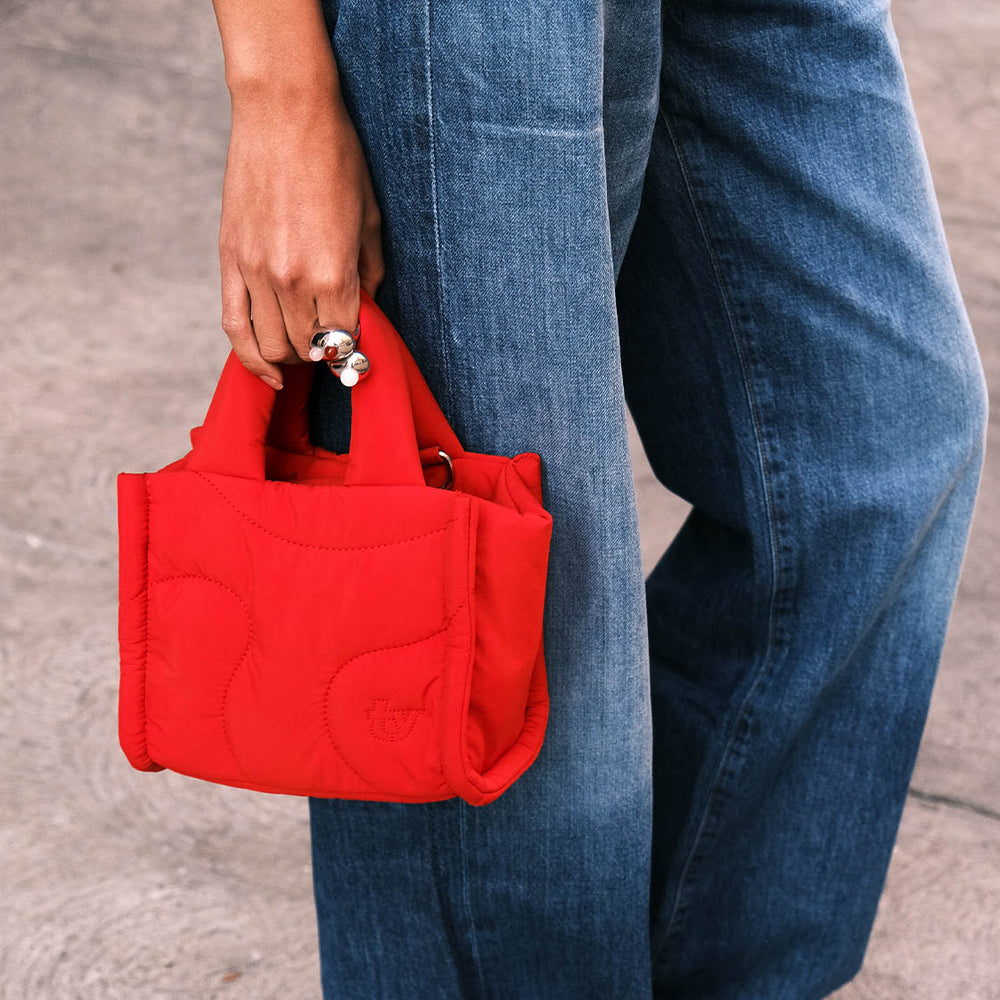 A woman in jeans holding a cherry red mini puffer tote