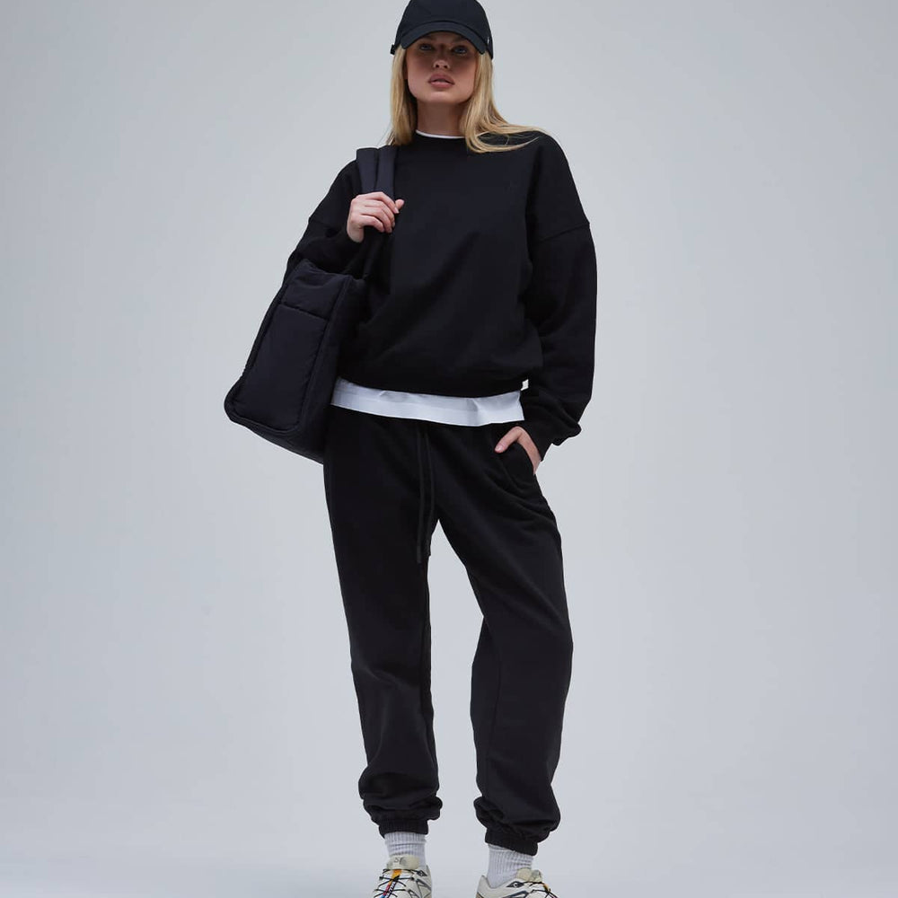 A woman in a relaxed sweatshirt and pants with sneakers and a bag