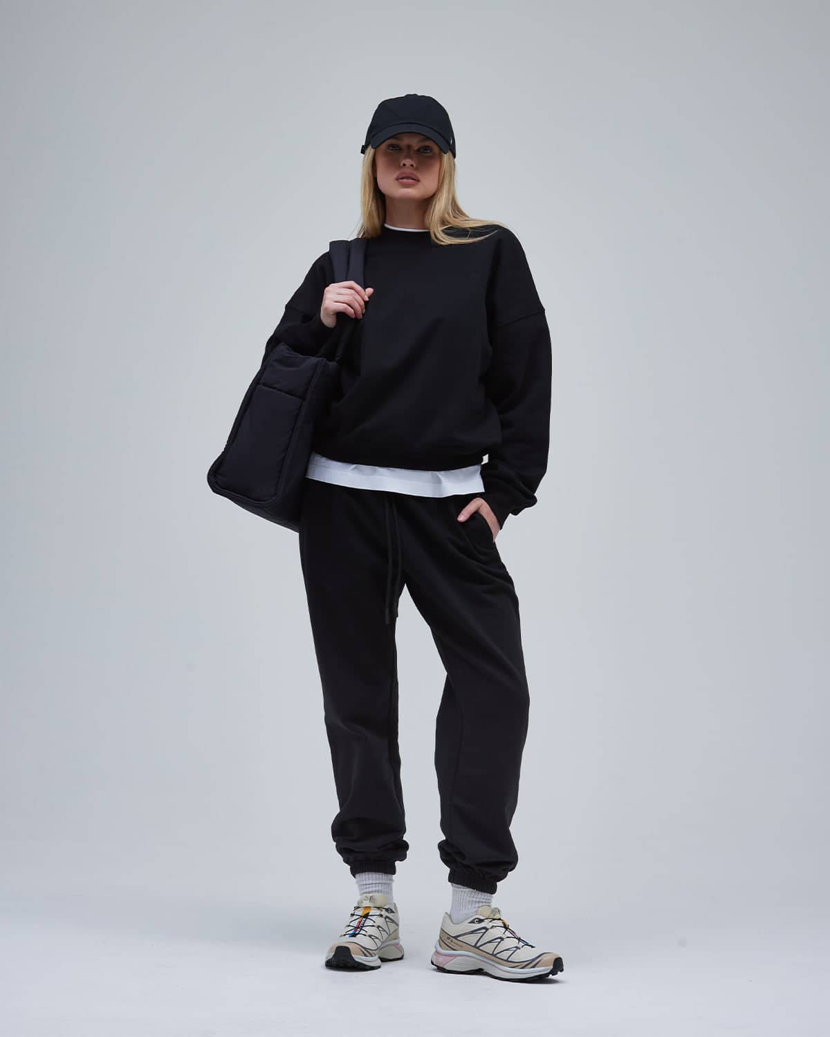 A woman in a relaxed sweatshirt and pants with sneakers and a bag