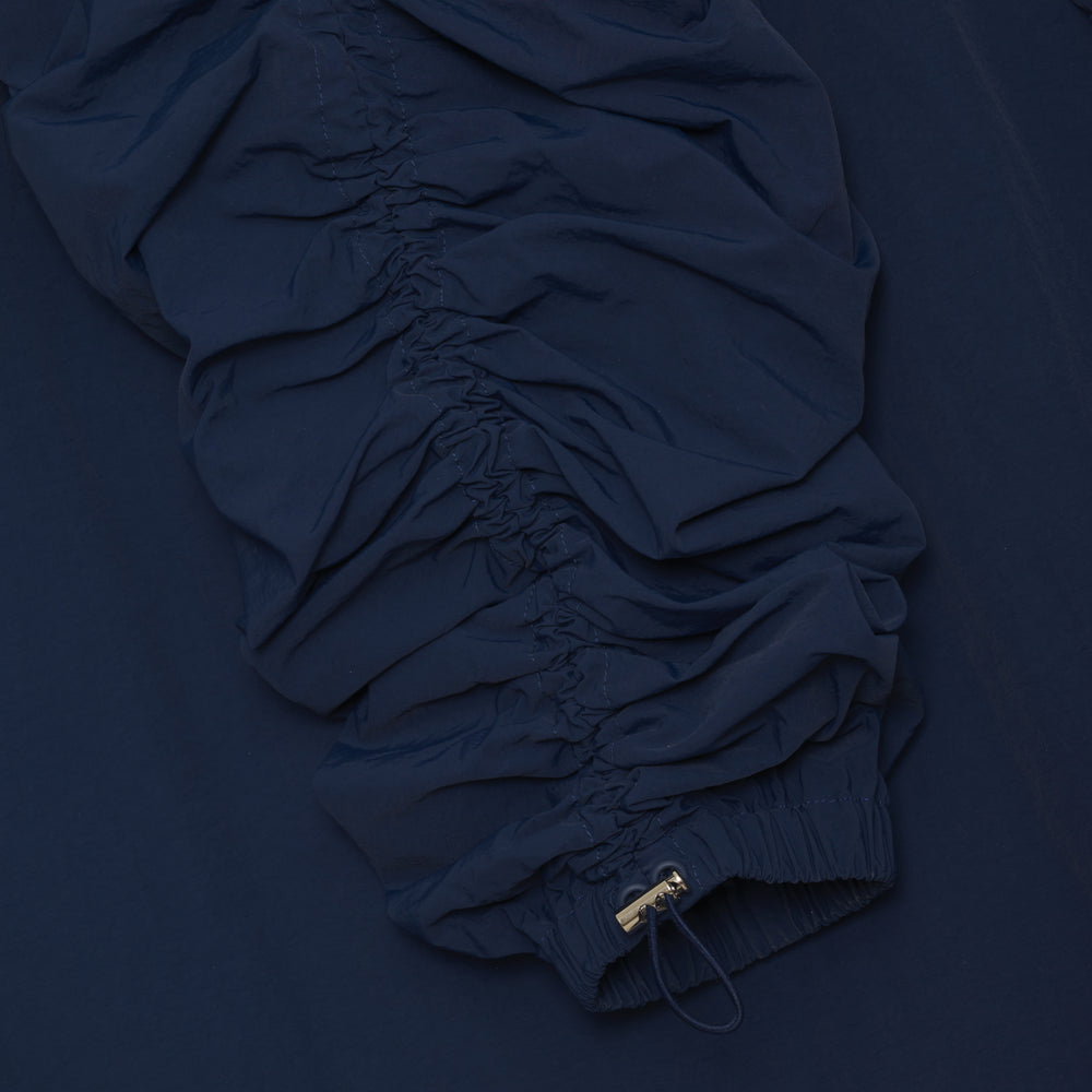 
                  
                    navy dark blue mid-length nylon trench jacket. fold over collar, two-way zip closure, bungee cinch at the waist, hem, two front pockets, two side seam pockets.
                  
                