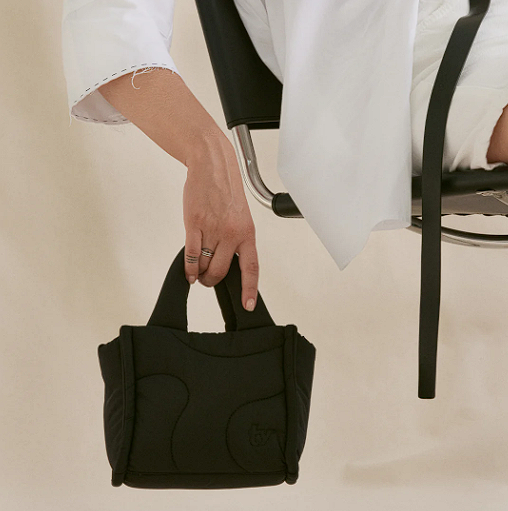 Person holding a puffer-design best-selling bag in black