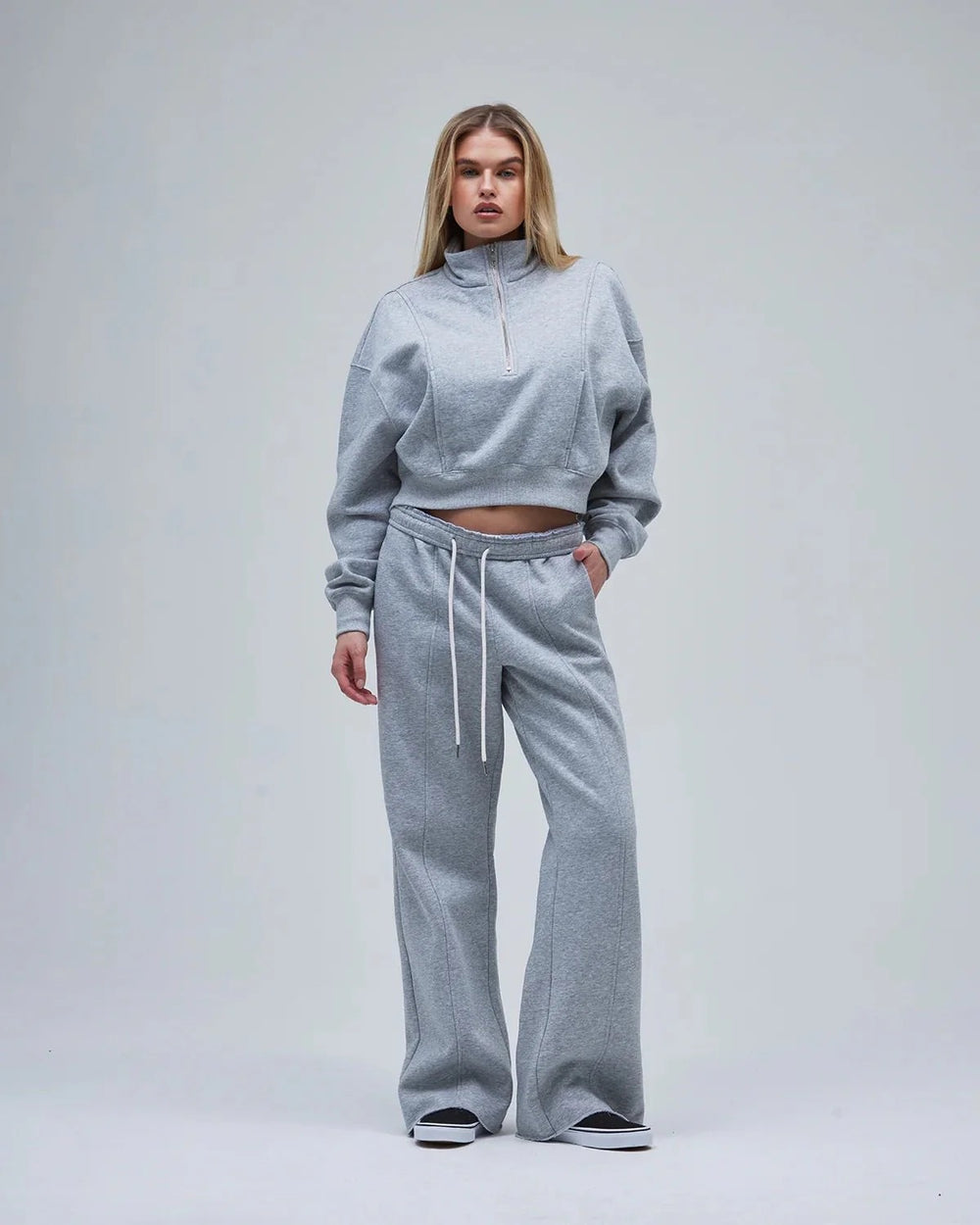 A woman in grey wide-leg sweatpants & a matching sweatshirt