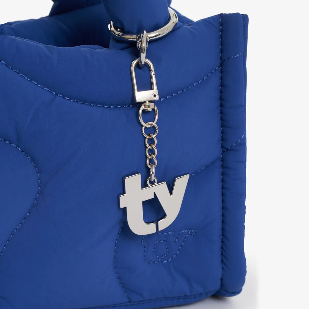 A Thirty Years “TY” silver bag charm on a blue bag
