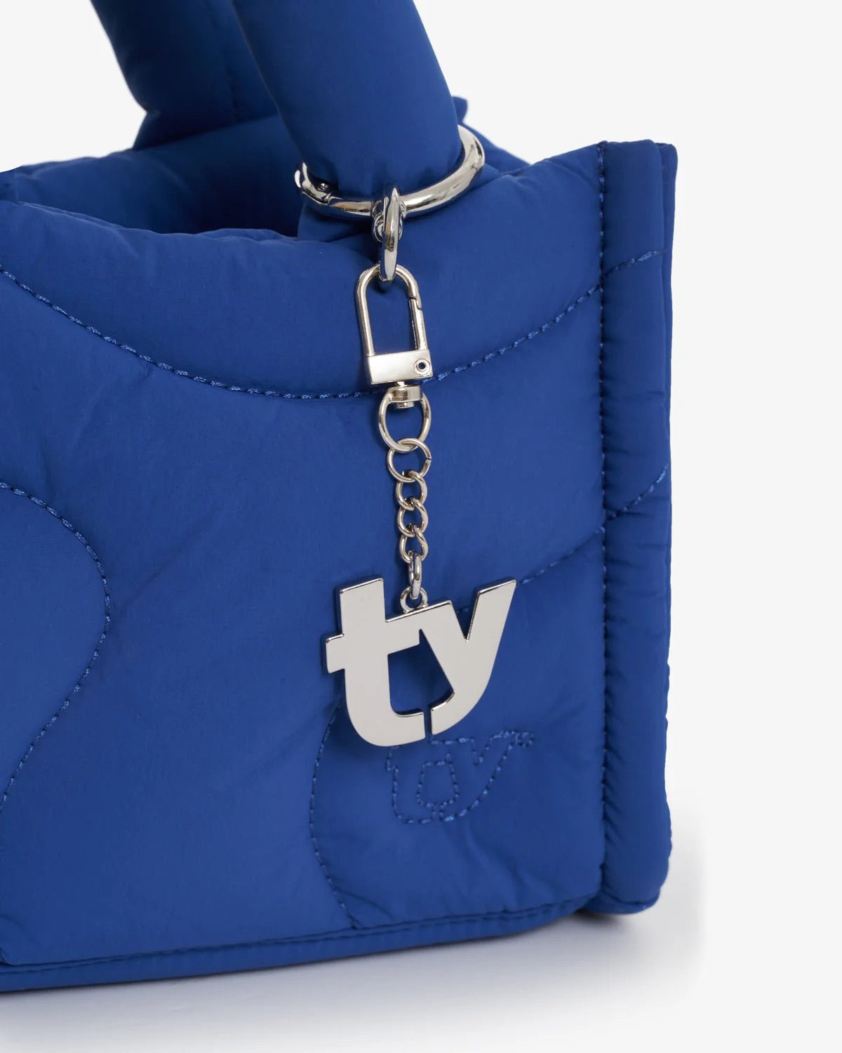 A Thirty Years “TY” silver bag charm on a blue bag