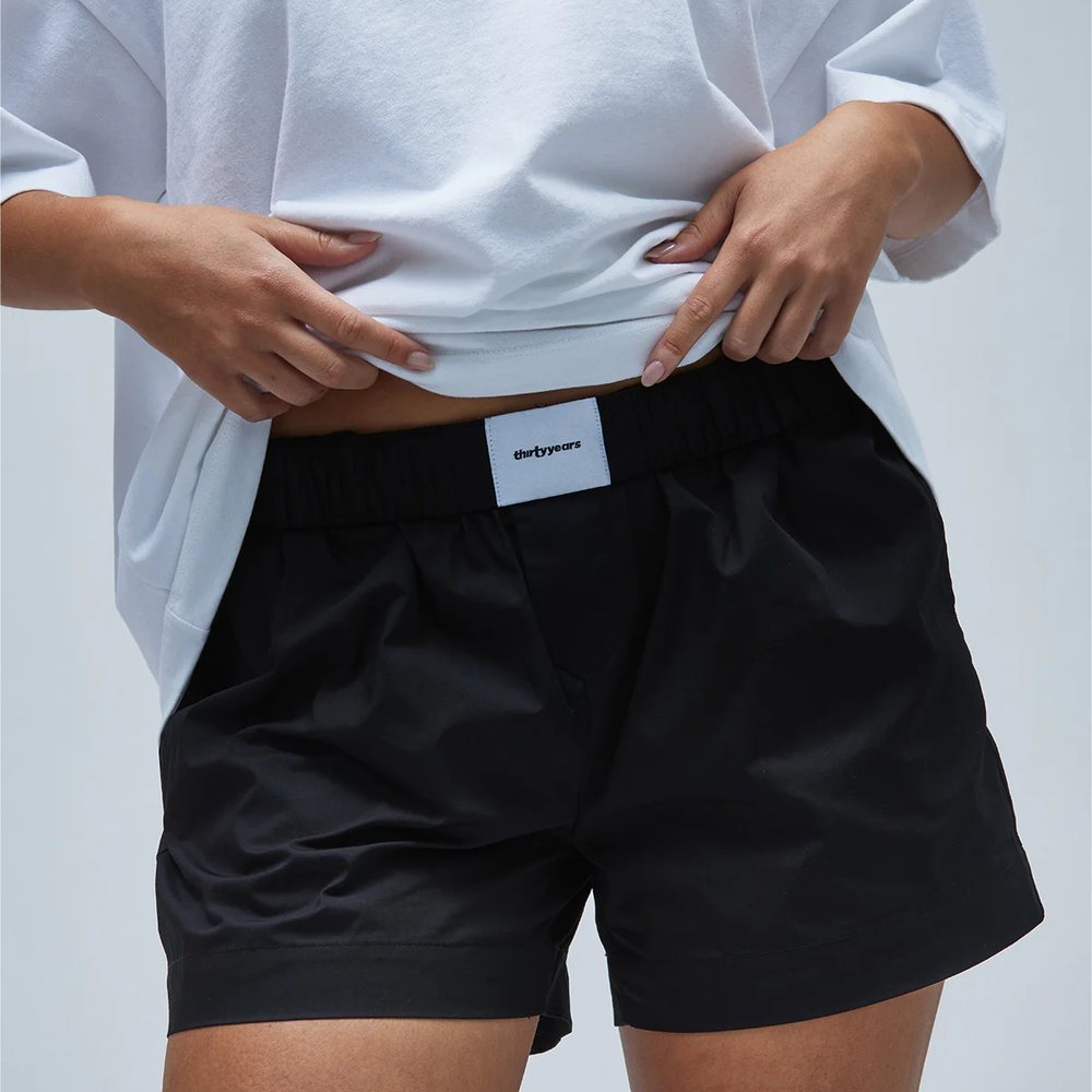 A model wearing black women's boxer-style shorts with a white tee