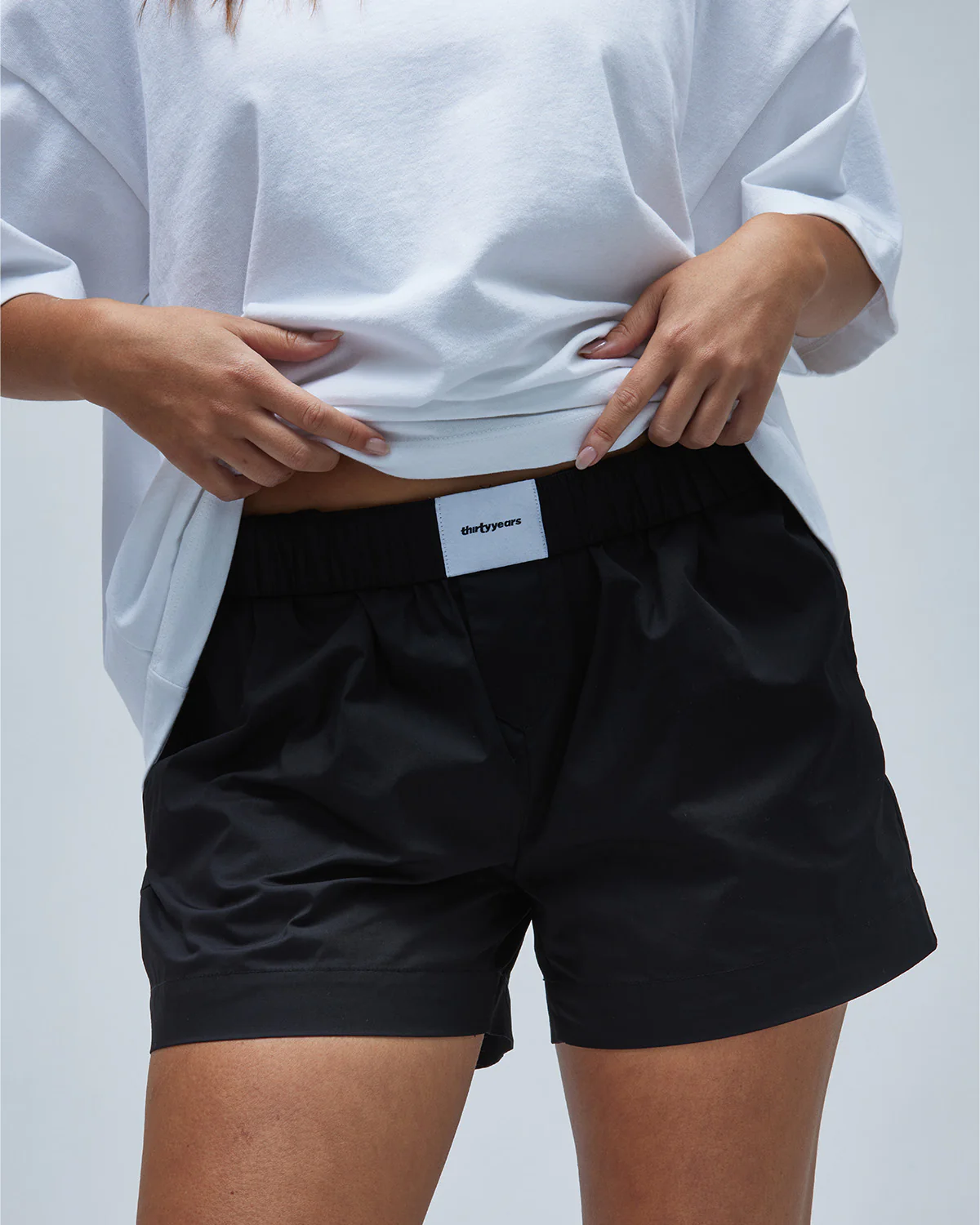 A model wearing black women's boxer-style shorts with a white tee